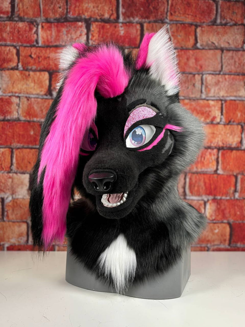 Fox fursuit  head with pink, black and gray hair against a brick wall background