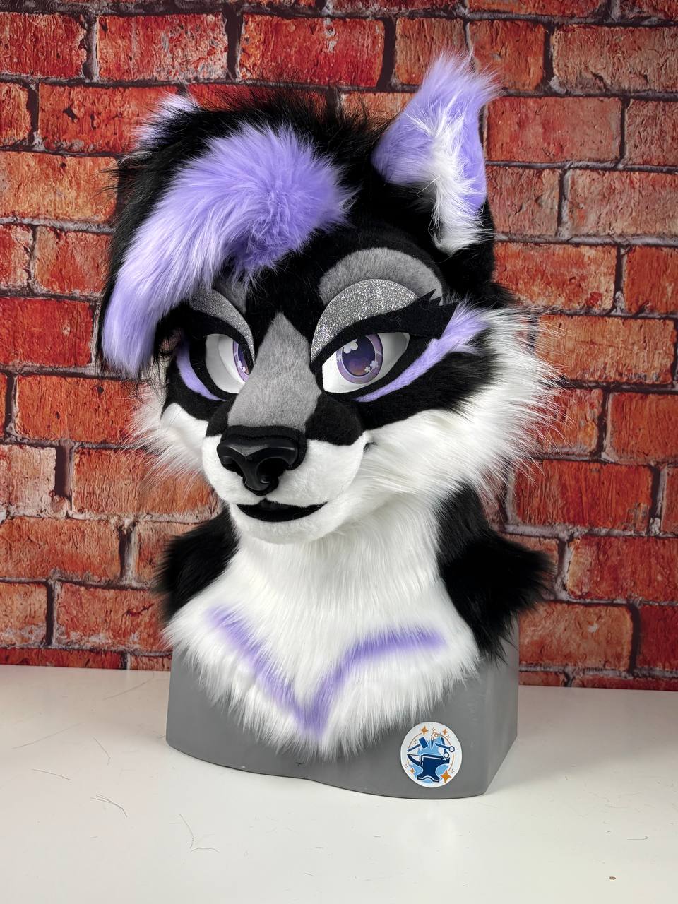 Cat Fursuit head with black, white, and purple fur against a brick wall background